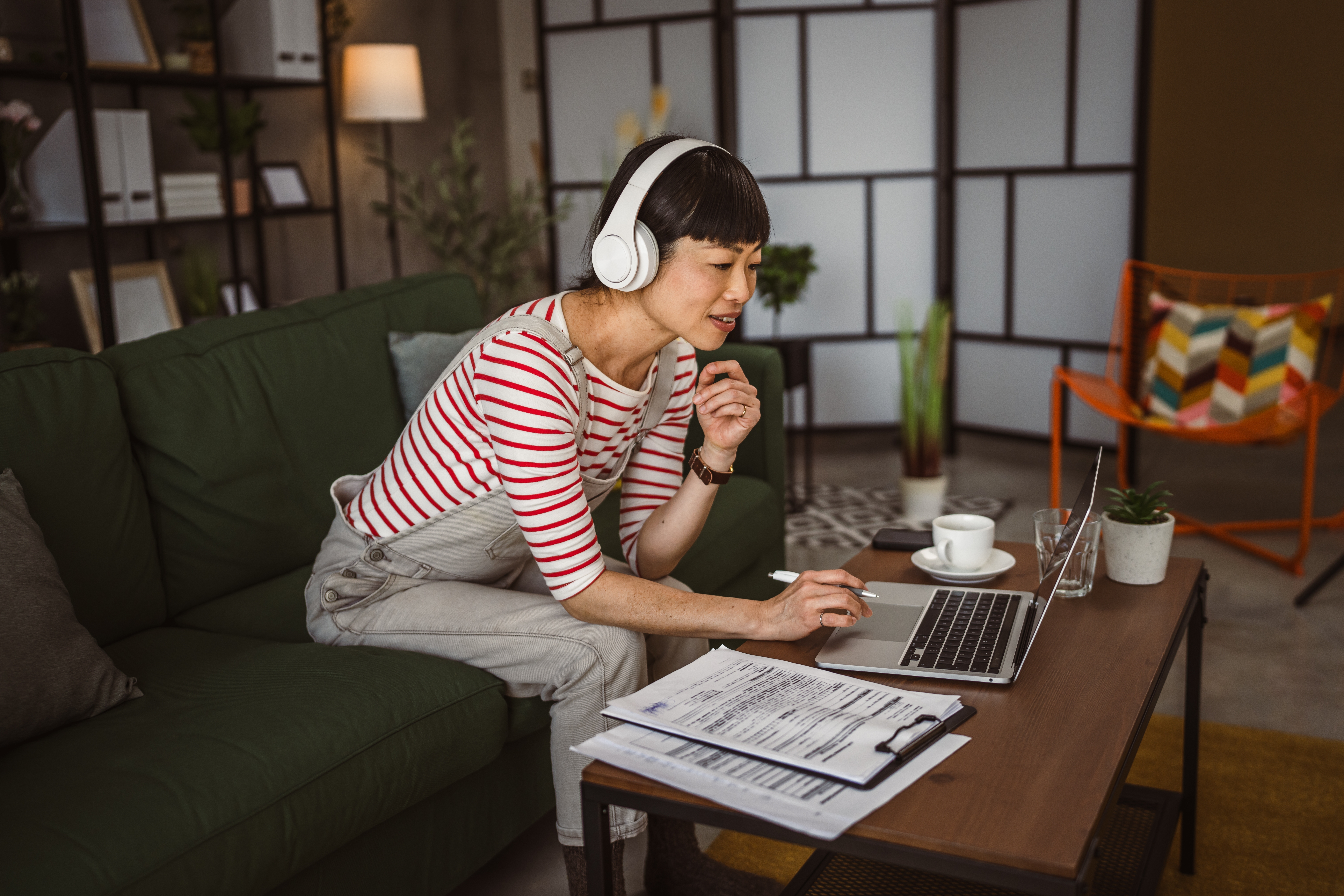 Woman in headphones sitting on her couch and talking to her instructor during an online group language lesson with Berlitz Saudi Arabia