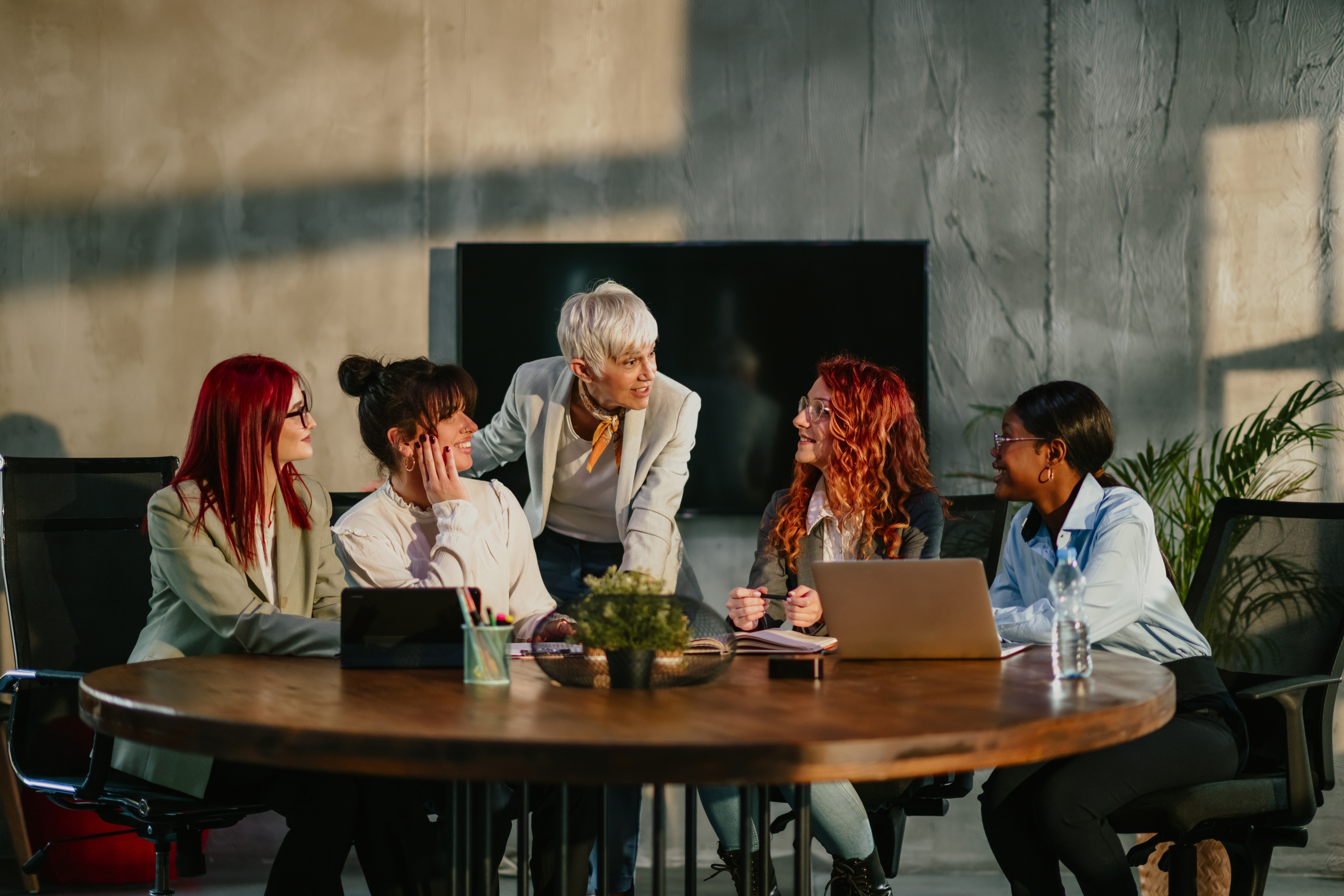 Instructor talking to her students who are sitting around a table during a training for government departments