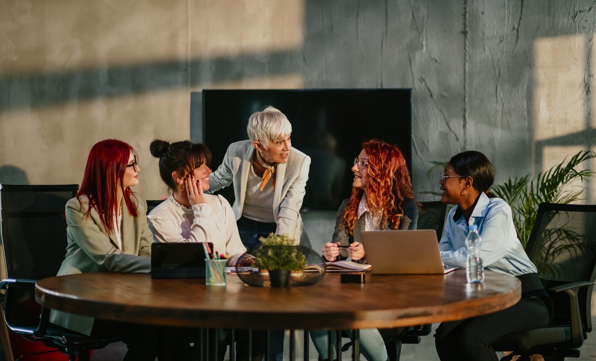 Instructor talking to her students who are sitting around a table during a training for government departments