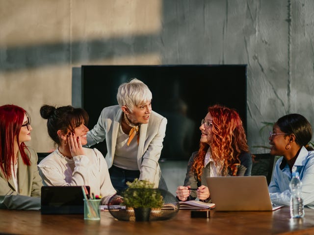 Instructor talking to her students who are sitting around a table during a training for government departments