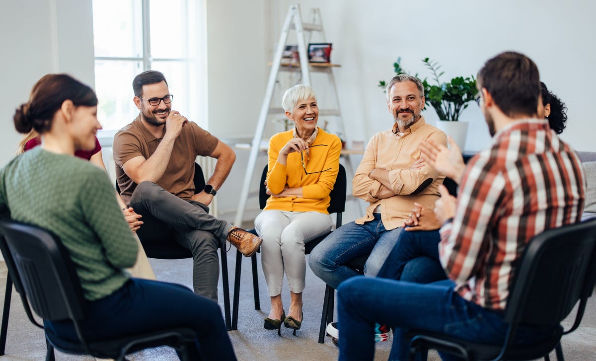 Group of students sitting in a circle and learning a language from their instructor using the Berlitz Method
