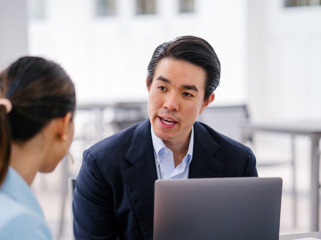 Student sitting in front of his laptop and talking to his instructor during one of their private language lessons