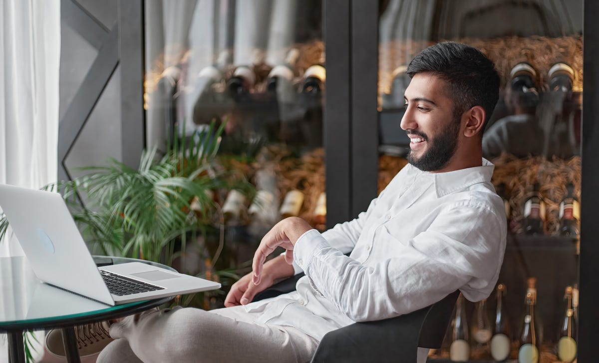 Man smiling while looking at his laptop during his online language courses with Berlitz