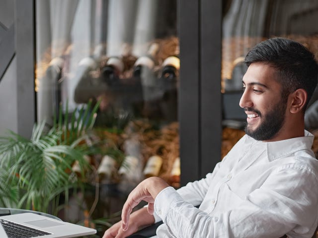 Man smiling while looking at his laptop during his online language courses with Berlitz