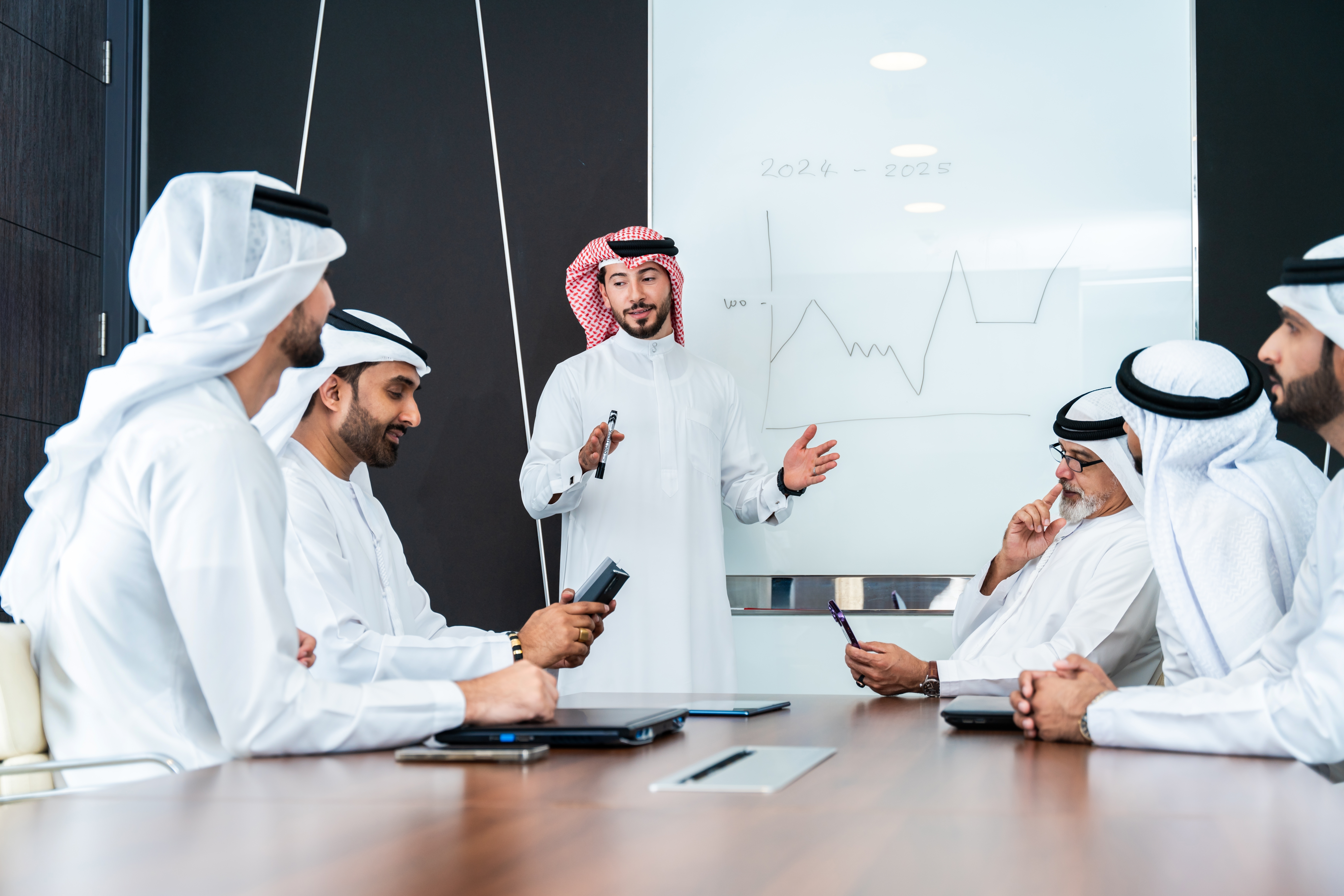 Group of men sitting around a table during a meeting and talking in a foreign meeting after their business language class with Berlitz Saudi Arabia