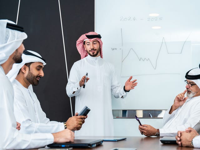 Group of men sitting around a table during a meeting and talking in a foreign meeting after their business language class with Berlitz Saudi Arabia