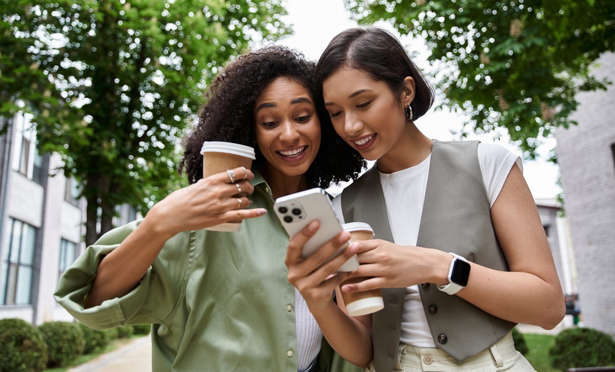Two women drinking coffee and checking out Berlitz Flex on their phones