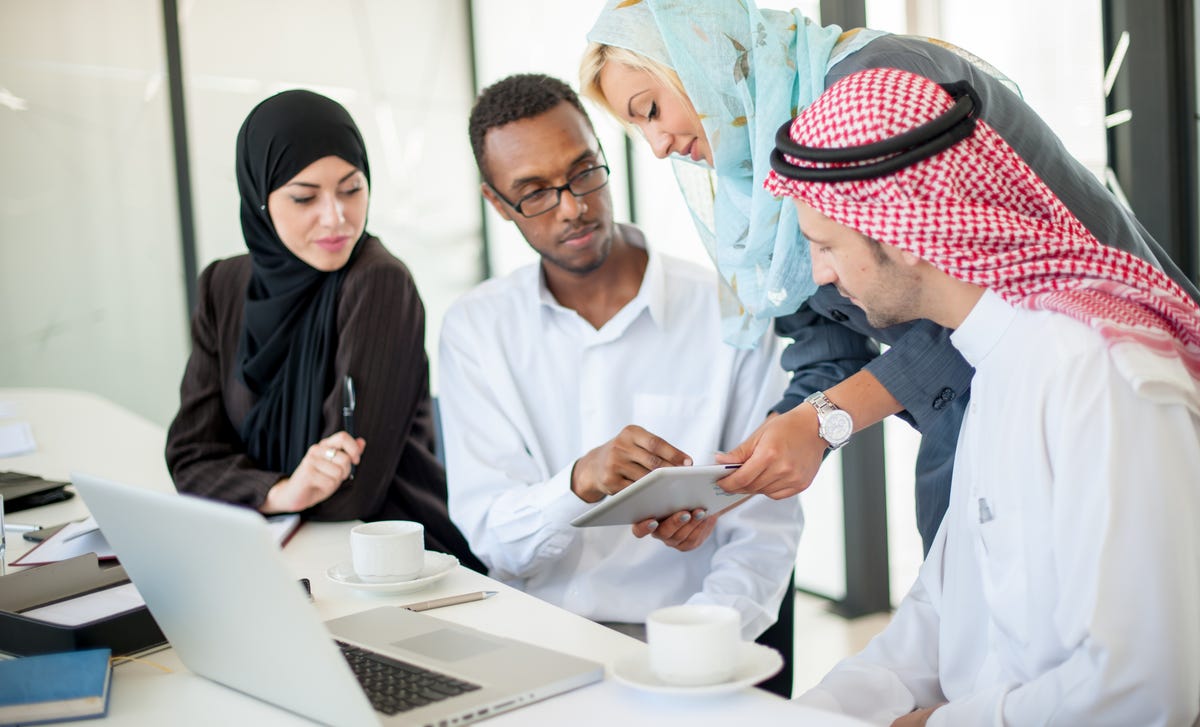 People talking to their instructor and looking at a paper together during a cross-cultural training for expatriates