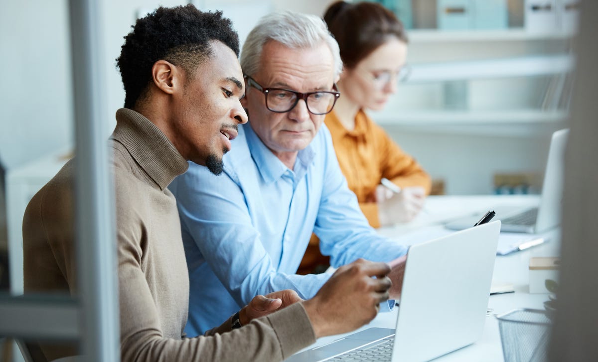 Two men in front of a laptop reading Berlitz Saudi Arabia's privacy policy together