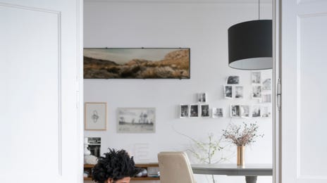 Man sitting at a door with a laptop in his lap and practicing his new language with Berlitz Flex