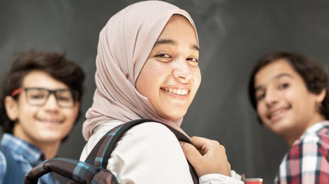 Kids standing next to each other and smiling while waiting for their language class with Berlitz Saudi Arabia to start