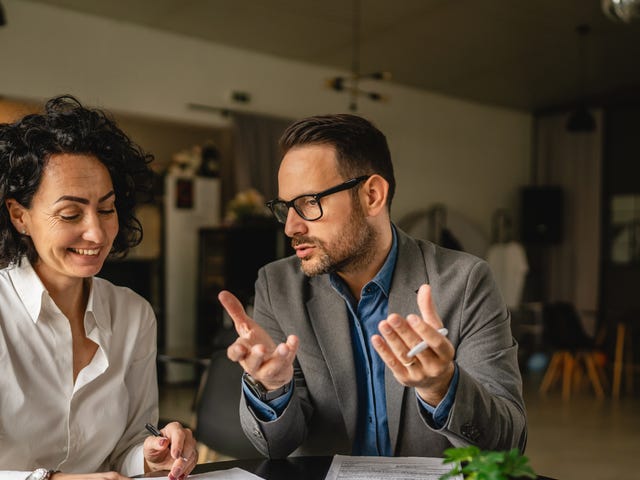 Student and instructor sitting at a table and looking at papers together during one of their intensive language courses