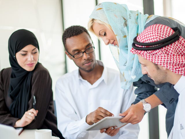Student talking to his instructor and showing him an exercise on a tablet during one of their English language classes
