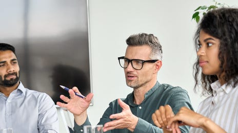 Employees sitting around a table and talking to their instructor during one of their business training seminars with Berlitz Saudi Arabia