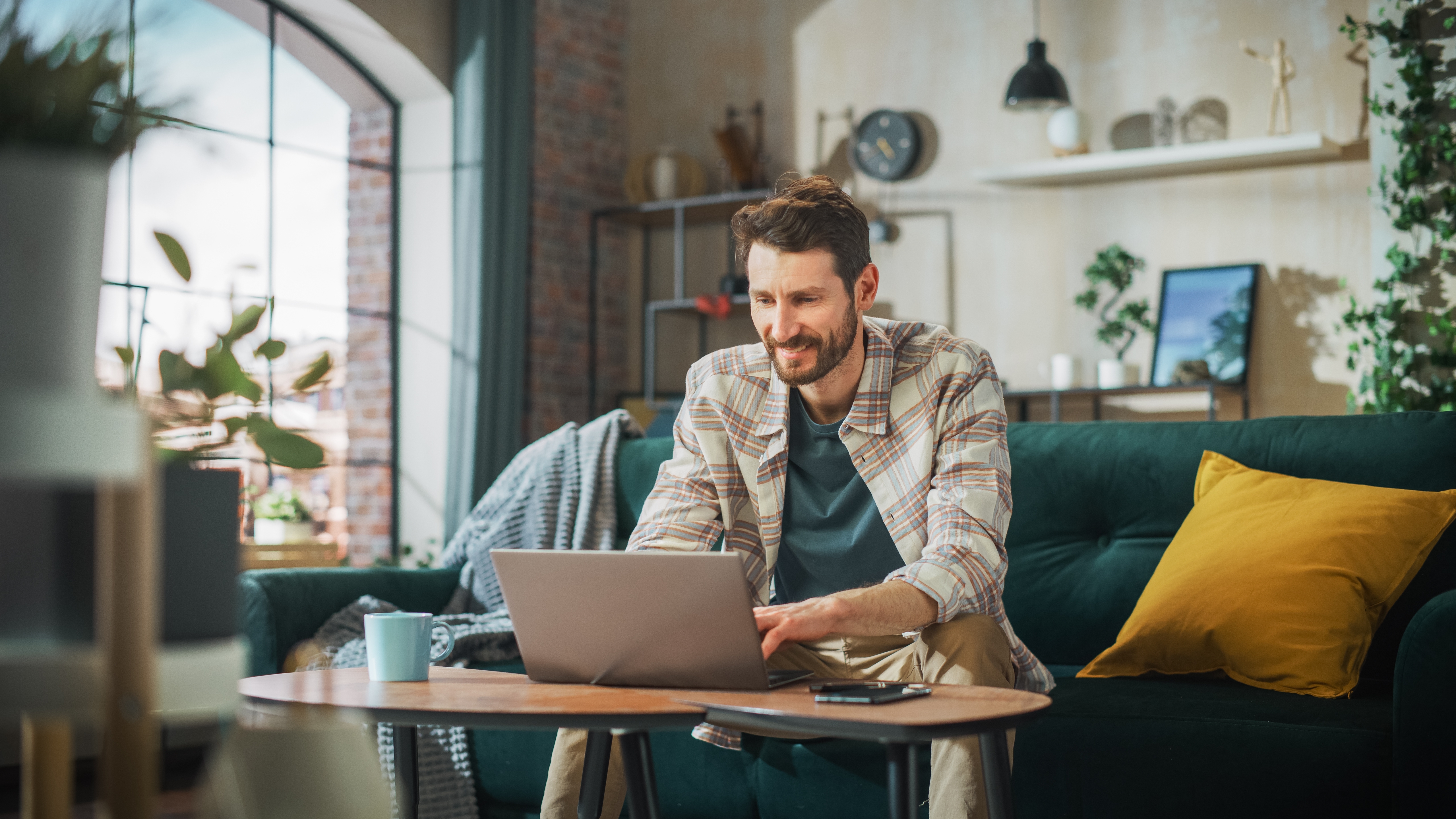 Man sitting on a couch and reading about the Berlitz Method on his laptop