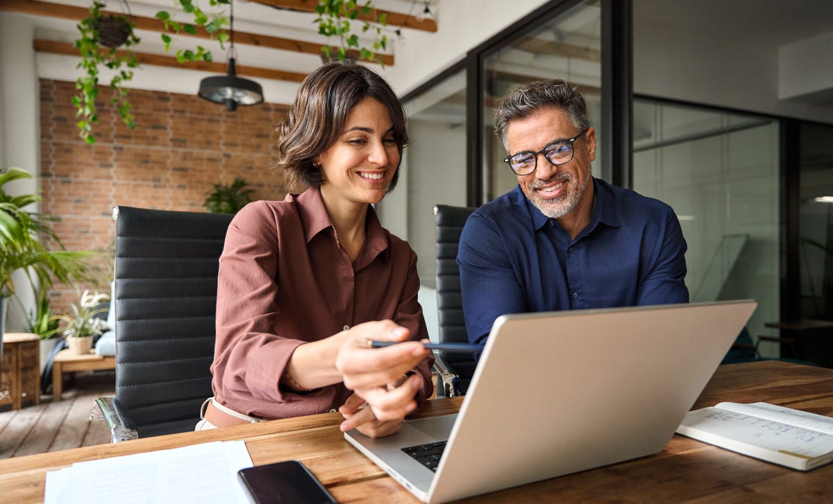 Instructor showing an exercise to her student on her laptop and explaining the solution during their Korean speaking course