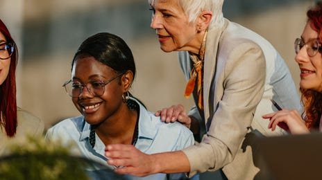Instructor standing next to her students and talking to them while they check an exercise together