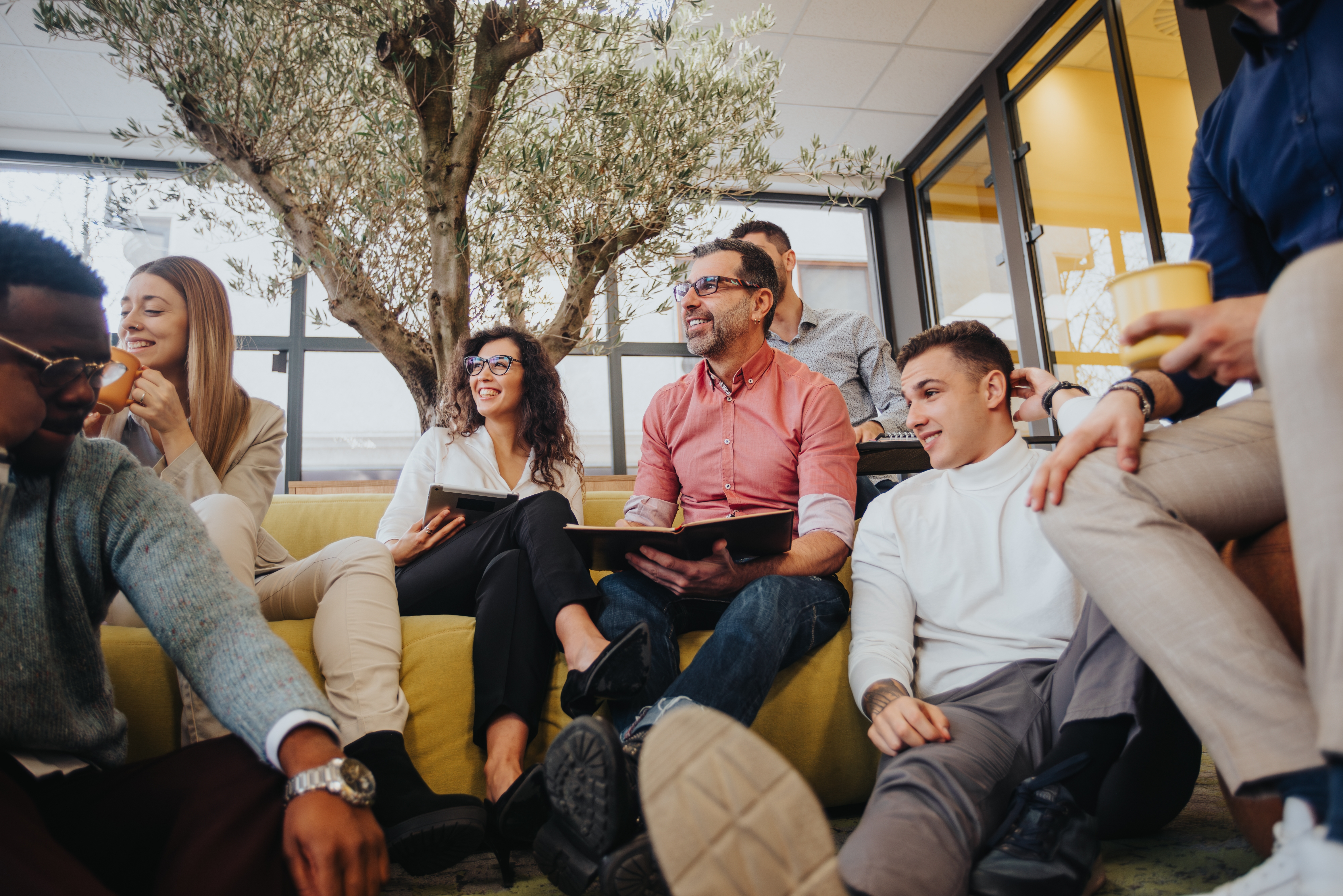 Group of people sitting on and around the couch during a language lesson for adults with Berlitz Saudi Arabia