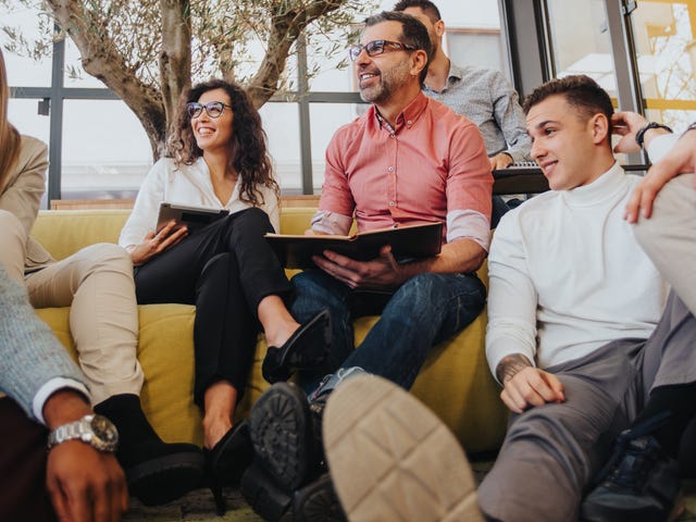 Group of people sitting on and around the couch during a language lesson for adults with Berlitz Saudi Arabia