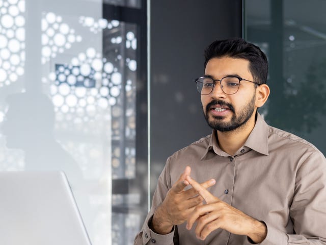 Man talking to his instructor during his online Business English class that he is attending from his laptop