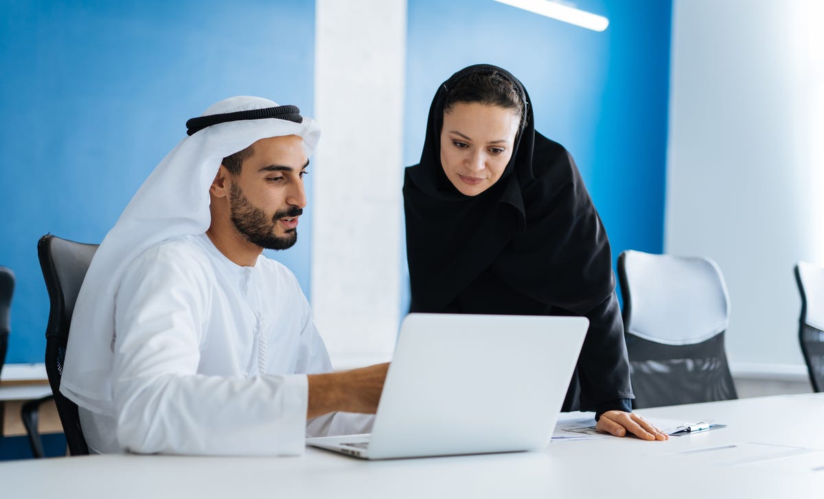 Student and instructor looking at a laptop together and doing a language practice during preparation for a language proficiency test