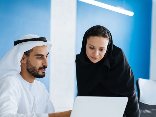 Student and instructor looking at a laptop together and doing a language practice during preparation for a language proficiency test
