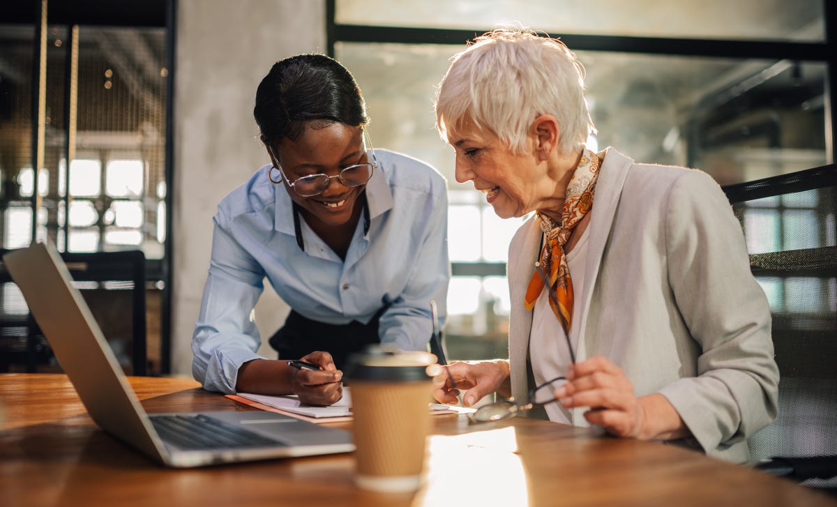 Two women in front of a laptop talking about Berlitz and making notes for themselves