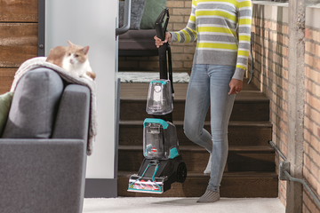 Woman carrying TurboClean PowerBrush Carpet Cleaner down stairs.