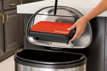 REFRESH Manual Sweeper being emptied into trash.
