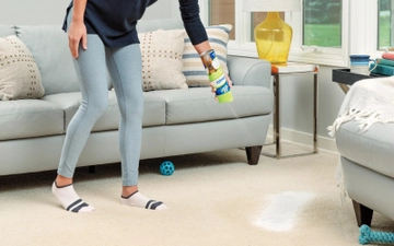 Woolite® Heavy Traffic® carpet foam being sprayed onto carpet prior to cleaning.