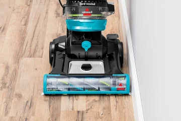 CleanView Swivel Rewind Pet Vacuum vacuuming hard flooring along baseboards.