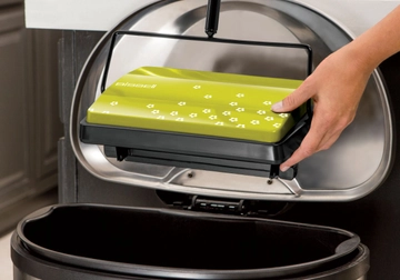 REFRESH Manual Sweeper being emptied out into trash bin.