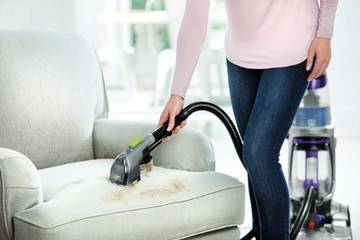 Using Trapper Tool on hose of upright carpet cleaner to pick up pet hair from couch cushion.