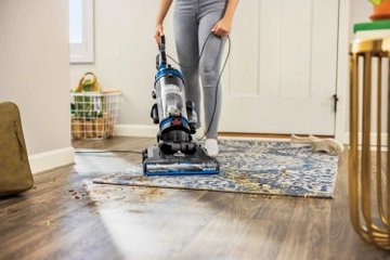 CleanView Upright Vacuum Cleaner vacuuming area rug in entry way. 