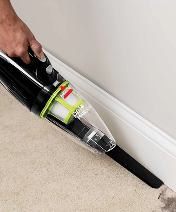 Using Crevice Tool to vacuum hair along baseboards