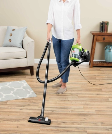 Carrying Zing Bagless Canister Vacuum across the room.