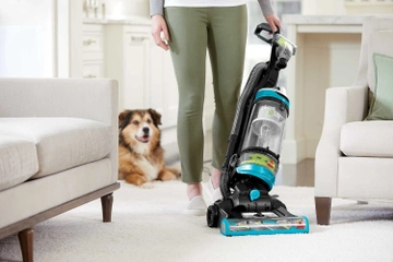 CleanView Swivel Rewind Pet Vacuum vacuuming carpet between furniture.