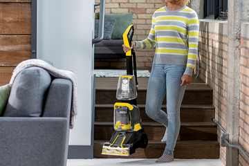 Woman carrying TurboClean PowerBrush Carpet Cleaner down stairs.