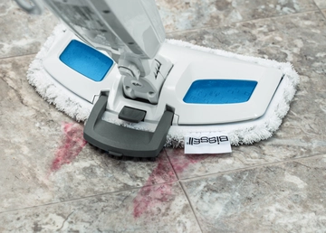 Using Scrubbing Brush on foot to steam sticky mess on tile flooring.