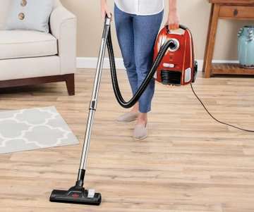 Person carrying Zing Bagged Canister Vacuum around room.