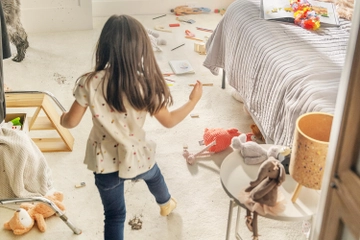 Girl walking through playroom with a spill on carpet.