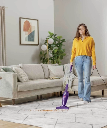 FeatherWeight Stick Vac vacuuming area rug.