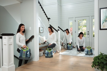 Woman using portable deep cleaner to clean stain off area rug, stairs, and couch.