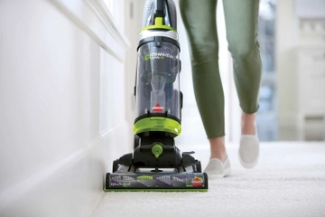 CleanView Swivel Pet Vacuum vacuuming carpet along baseboards.