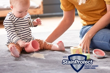 Baby and mom on carpet with spill on carpet and StainProtect Logo