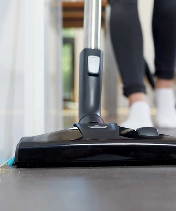 SmartClean Canister Vacuum Vacuuming along baseboard with edge cleaning bristles.   