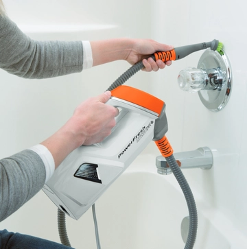 Using extension hose on handheld steamer to steam shower area.