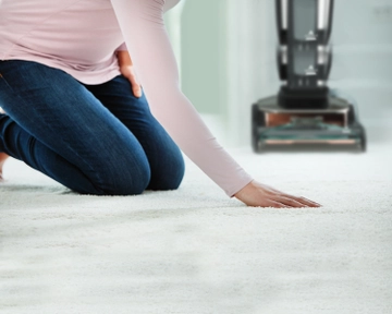 Running hand across dry carpet with Upright Carpet Cleaner in background.