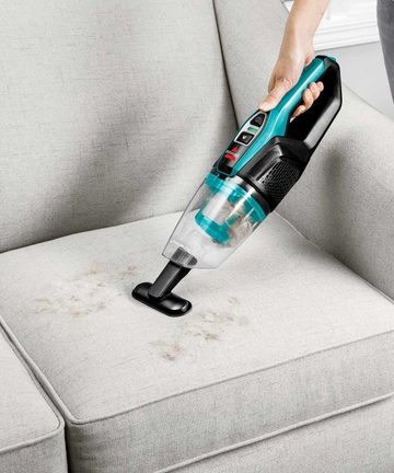 Using ReadyClean Cordless Stick Vac as a Hand Vac with combined crevice tool and dusting brush to vacuum couch cushion. 