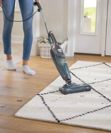 Featherweight Stick Vac vacuuming area rug in entry way